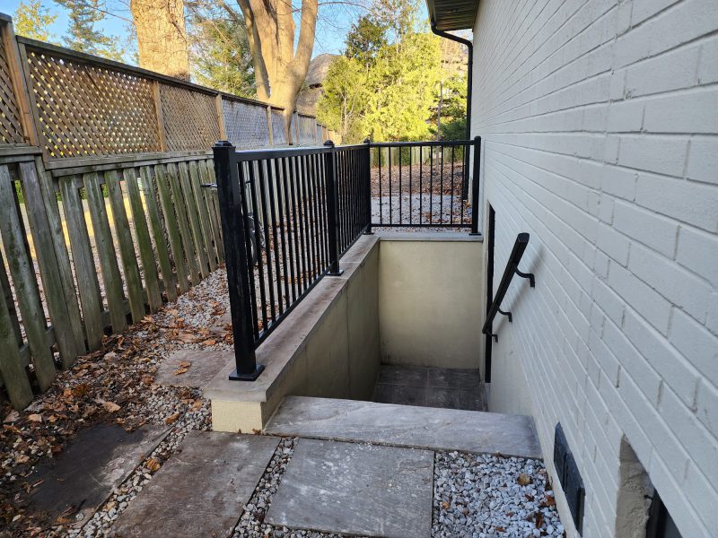 Basement walkout entrance with concrete stairs and black railing