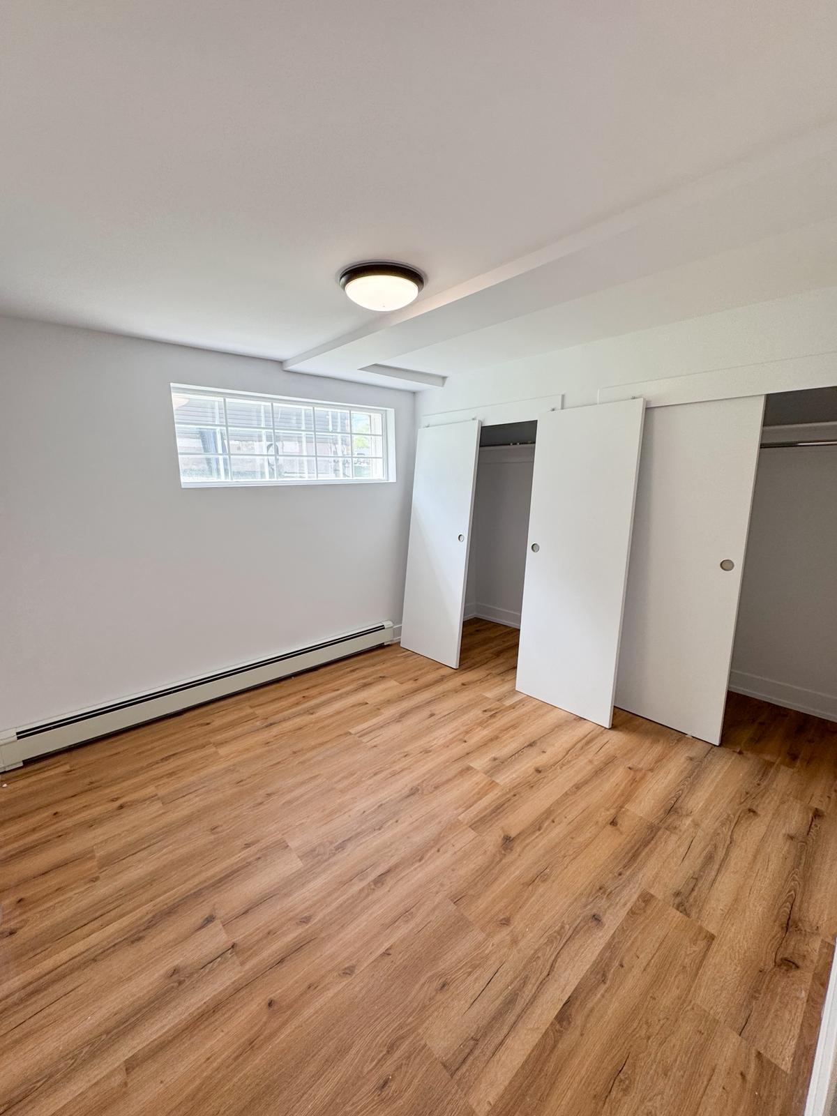 Finished basement bedroom with egress window, closets, and LVP flooring