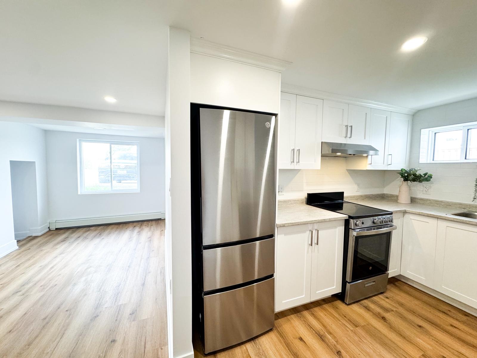 Finished basement kitchen with stainless steel appliances, white shaker cabinets, granite countertops, subway tile backsplash