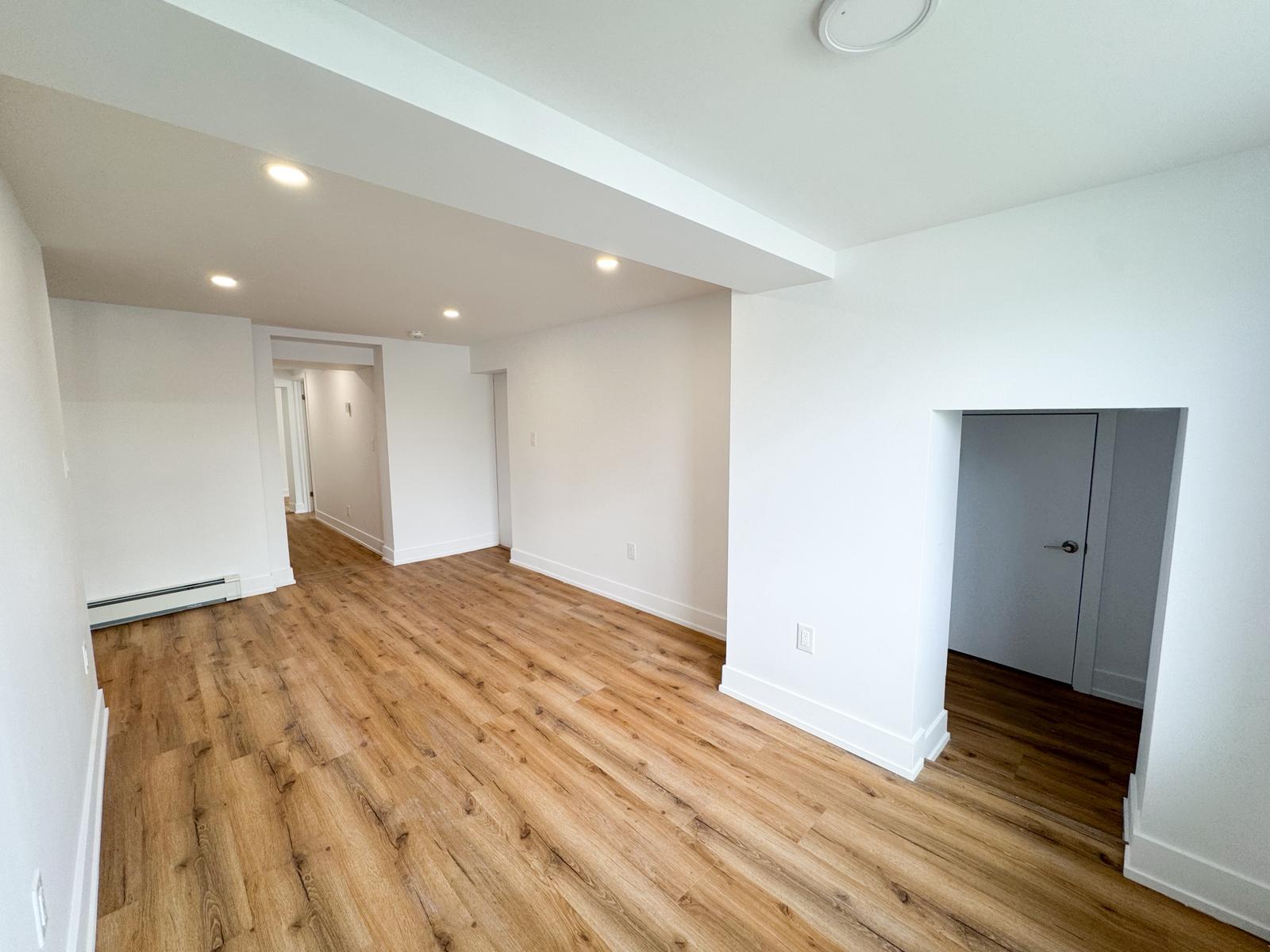 Finished basement living area with recessed lighting, hardwood floors, multiple rooms
